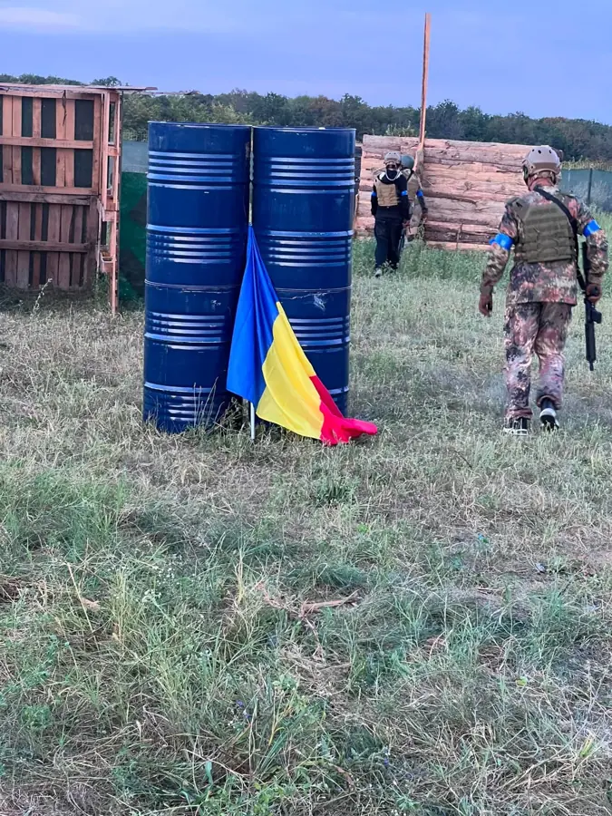 Butoaie albastre stivuite, cu tricolorul lângă ele